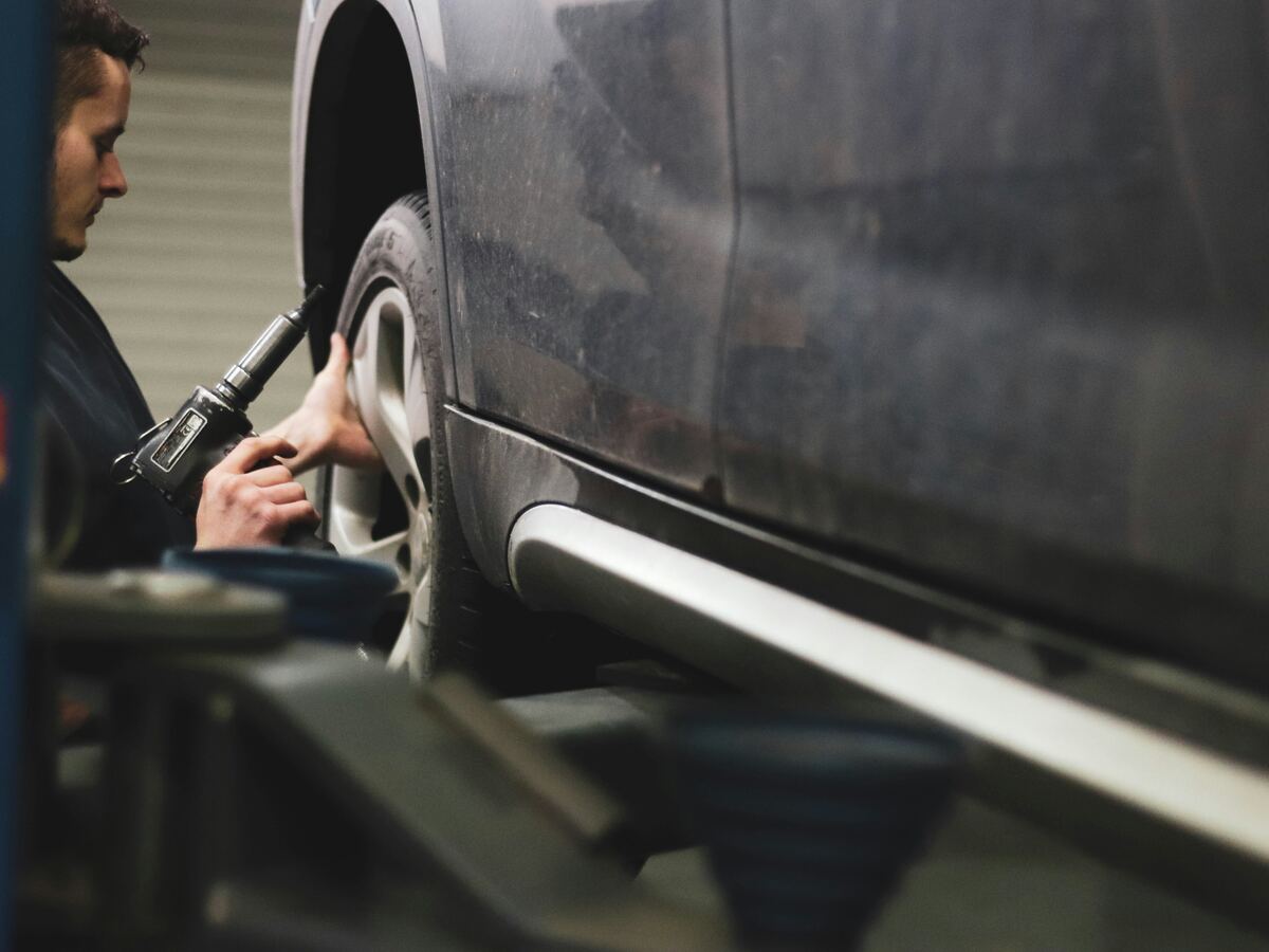 Techniker prüft Reifen und Rad eines Fahrzeugs in der Werkstatt